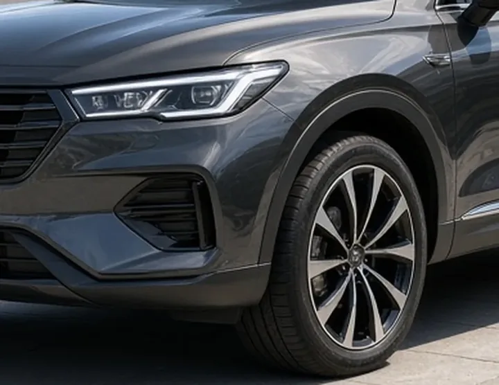 Close-up of a glossy dark grey car's headlight, front bumper and alloy wheel